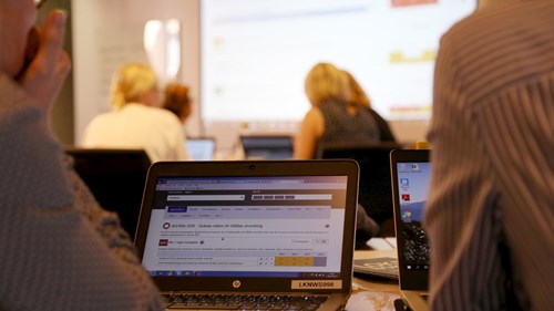 En dataskärm med Kolada i förgrunden, andra deltagare smed datorer i bakgrunden