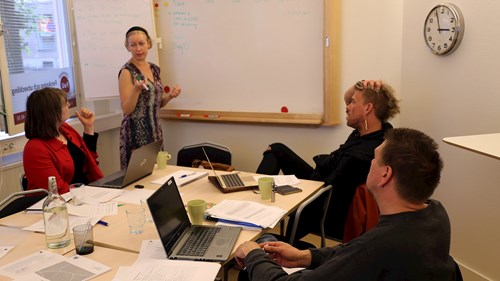 Marie skriver på en whiteboard och de andra mötesdeltagarna kommer med förslag.