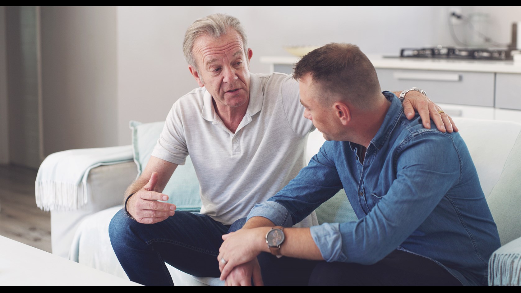 Två män sitter och pratar i en soffa